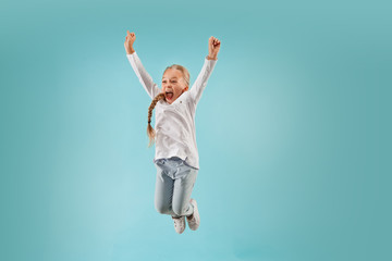Adorable small child at blue studio. The girl is jumping and smiling. Young emotional surprised...