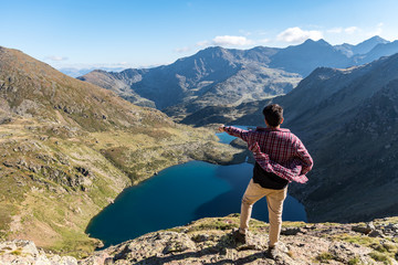 Men travel man standing on high mountain, hiking trip. Tristaina high mountain lakes in Pyrenees. Andorra