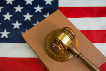 Hammer of the judge on the book of laws, the background of the flag of the United States of America. Court, law, crime and punishment, gavel.