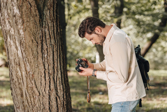 side view of young traveler with photo camera in park