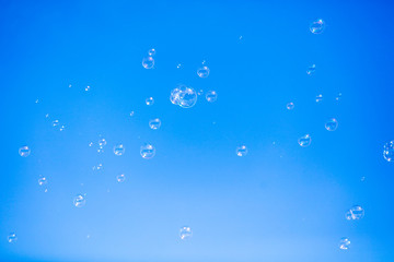 Soap bubbles in flight against the blue sky