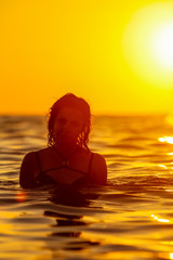 Fototapeta premium A girl is floating in the sea at sunset