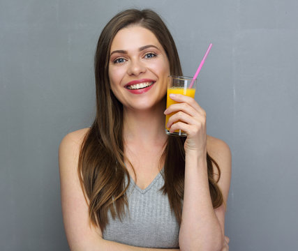 Young smiling woman holding orange juice glass with straw.