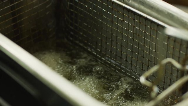Placing food in a deep fryer in a slow motion close up