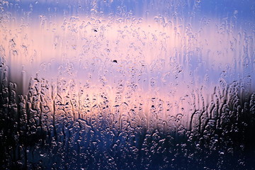 Raindrops on the glass at sunset. Rainy weather forecast.