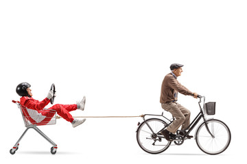 Elderly man in a racing suit inside a shopping cart being pulled by another elderly man on a...