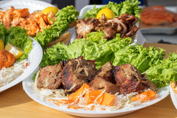 Shashlik, grilled meet with vegetable, plate un the forground with grilled meet, green leafes of lettuce, cabbage and carrote, rear plate with drilled octopuses, lemon and lettuce.