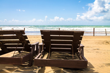 Two wooden sun beds are deployed to the ocean. The coast of the Atlantic Ocean. The beach is near...