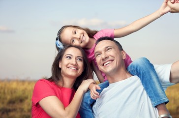 Obraz premium Happy smiling family with daughter on autumn background