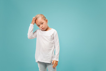 Fototapeta premium Why is that. Beautiful female half-length portrait on trendy blue studio backgroud. Young emotional surprised, frustrated and bewildered teen girl. Human emotions, facial expression concept.