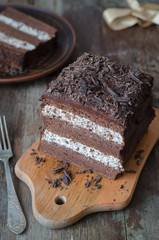 Layered chocolate cake with stracciatella cream on a rustic wooden background, cut out, selective focus