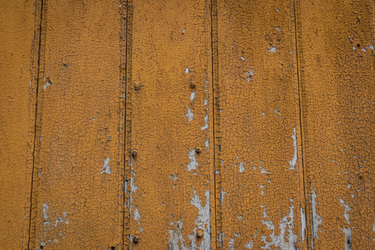 Weathered orange paint blistering off wooden plank background detail