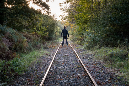 Strong male standing on old railroad track in the ardennes forest in autumn