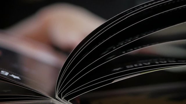Close-up of a woman leafing through pages in a restaurant or cafe menu.