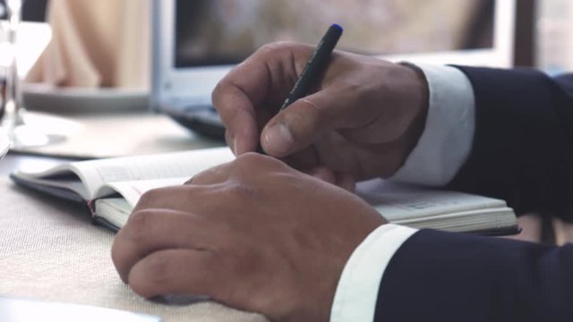 Businessman making notes in his organizer in restaurant or hotel