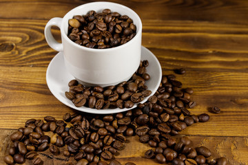 Coffee beans in white cup on wooden table