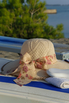 Close up of summer hat, towel and sun protection cream on a deck chair