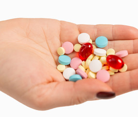 Multicolored pills in female hand, close-up, isolated on white background