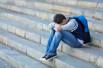 Schoolboy crying in the yard of the school