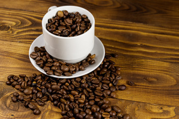 Coffee beans in white cup on wooden table
