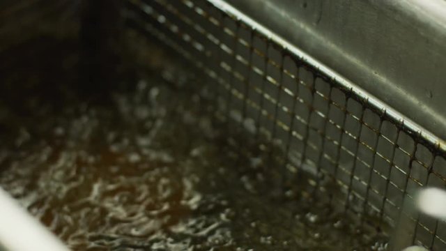 Removing food from a deep fryer in a slow motion close up
