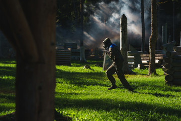 player in paintball in gear and with a game marker on a special playing field with fortifications. 