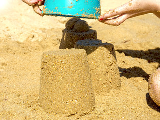 Closeup of a child hand, playing in the sand. Sand castle on the beach