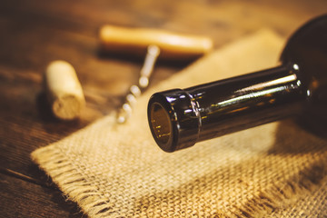 the neck of a bottle of wine. corkscrew and cork. wooden background.