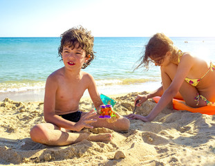 Brother and sister making sand castle at tropical beach