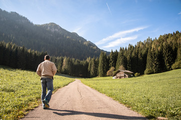a man alone walks towards a mountain forest