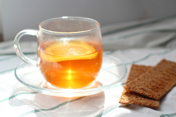 transparent Cup of tea with lemon, rye crispbread, natural light, breakfast