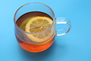 transparent Cup of tea with lemon on blue background