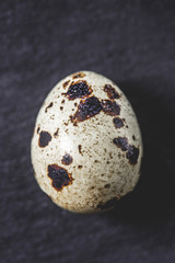 top view of organic unshelled quail egg on black, close-up view