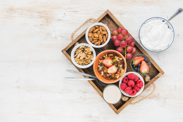 Top view of paleo grain free nut and fruit granola in a tray with fruits and berries, nut milk, coconut yogurt, copy space, top view, selective focus