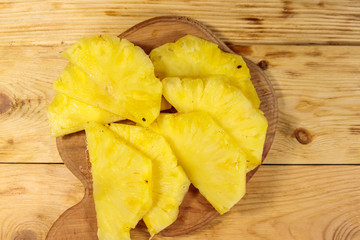 Pieces of pineapple on a cutting board on wooden table. Top view
