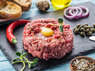 Steak tartare served with raw quail egg yolk, capers and bread. Meat dish.