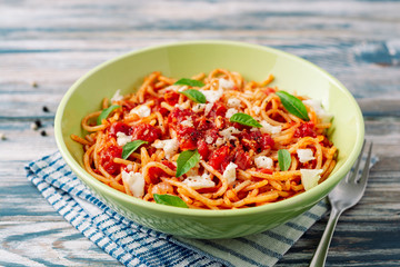 Spaghetti pasta with tomato sauce, mozzarella cheese and fresh basil leaves on white-blue vintage wooden background. Selective focus.