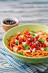 Spaghetti pasta with tomato sauce, mozzarella cheese and fresh basil leaves on white-blue vintage wooden background. Selective focus.