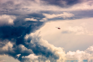 Obraz premium A small red helicopter in a dramatic blue sky