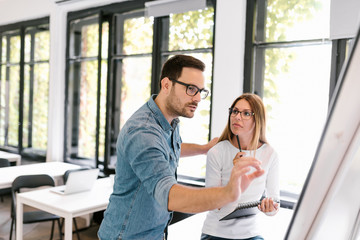 Fototapeta premium Beautiful business woman and man working with flipchart.
