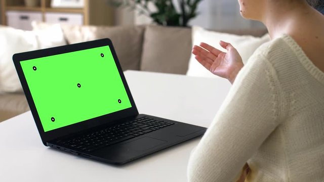 technology, communication and people concept - woman having video conference at home with chroma key green screen on laptop computer