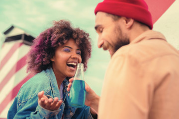 Too funny. Cheerful young people enjoying blue lemonade and laughing at the funny joke