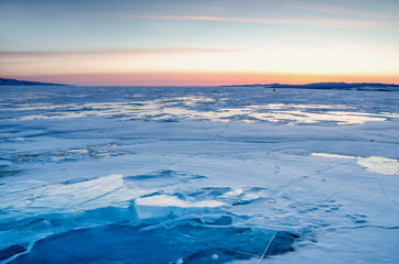 Walking in winter on the ice and snow texture. Sunset and silhouettes of people