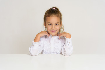 Fototapeta premium Portrait of a cute baby girl on a white background at the table.
