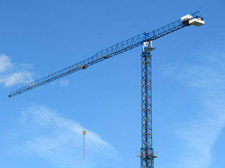 Construction crane against blue sky with white clouds