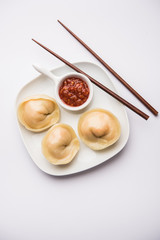 Dumpling momos food from Nepal or Ladakh served with red chilli chutney over moody background. Selective focus
