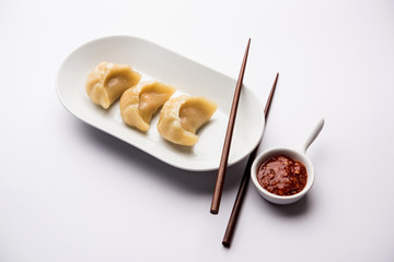 Dumpling momos food from Nepal or Ladakh served with red chilli chutney over moody background. Selective focus