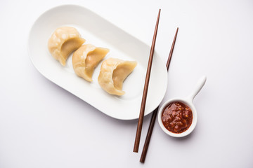 Dumpling momos food from Nepal or Ladakh served with red chilli chutney over moody background....