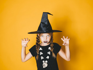 young halloween witch on orange background with black hat