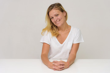 Fototapeta premium Portrait of a beautiful girl on a white background at the table.